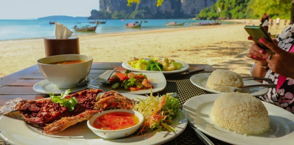 Fried fish and Thai food on table on the beach at Railay beach, Krabi, Thailand, healthy eating concept